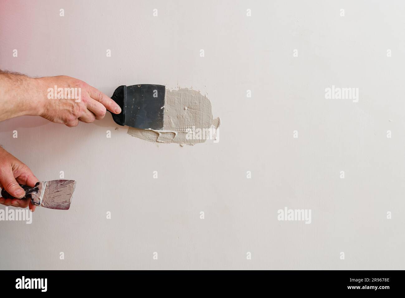 Repairing Holes In Drywall A Handyman Is Repairing A Hole In The