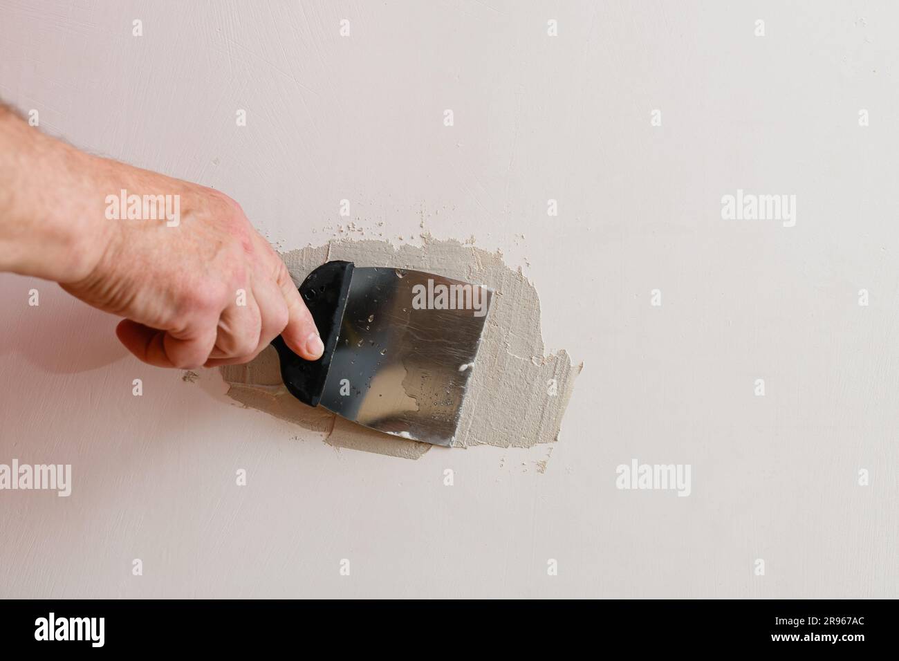Repairing holes in drywall. A handyman is repairing a hole in the