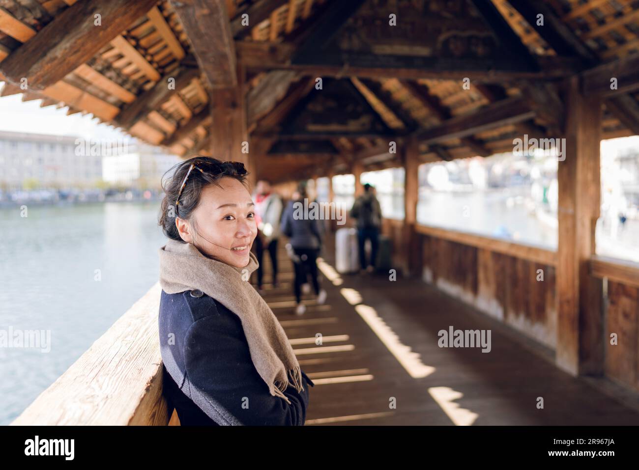 A woman standing on Chapel Bridge. The Chapel Bridge is a covered wooden footbridge spanning the river Reuss diagonally in the city of Lucerne in cent Stock Photo