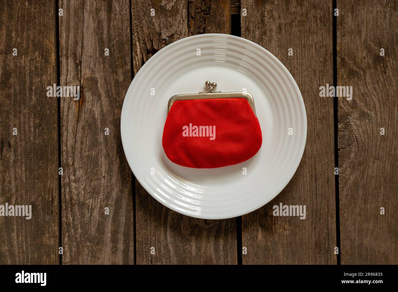 red wallet lies on a white plate on the table close-up Stock Photo
