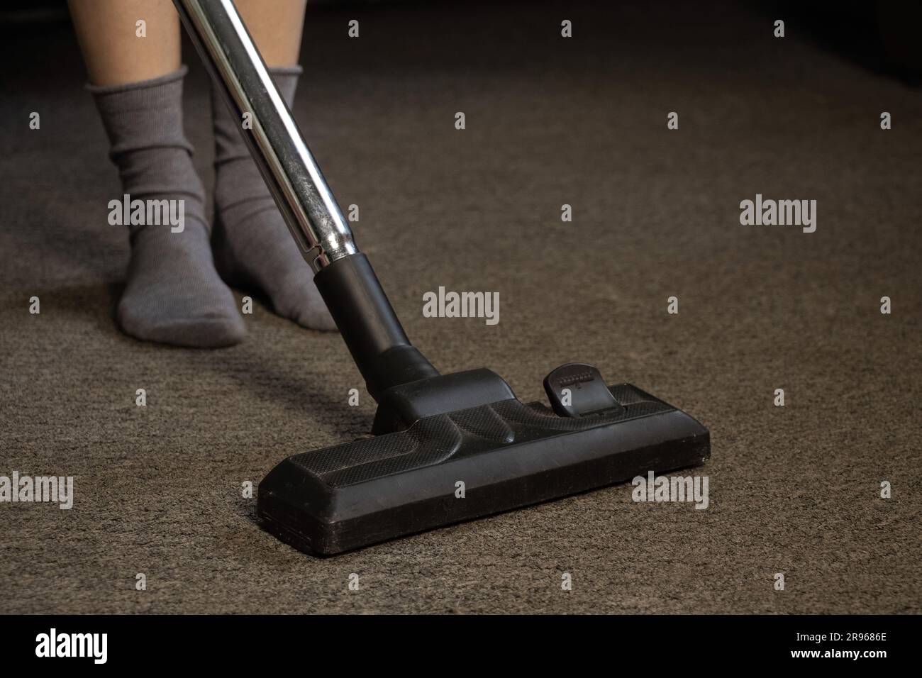 female feet in socks on carpet and vacuum cleaner, cleaning the