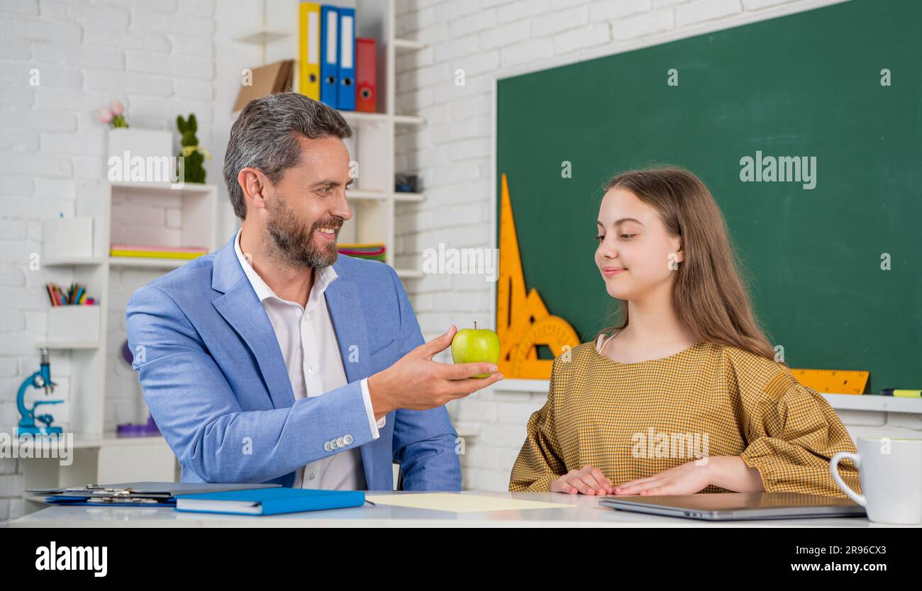 happy child in classroom with tutor sharing apple Stock Photo - Alamy