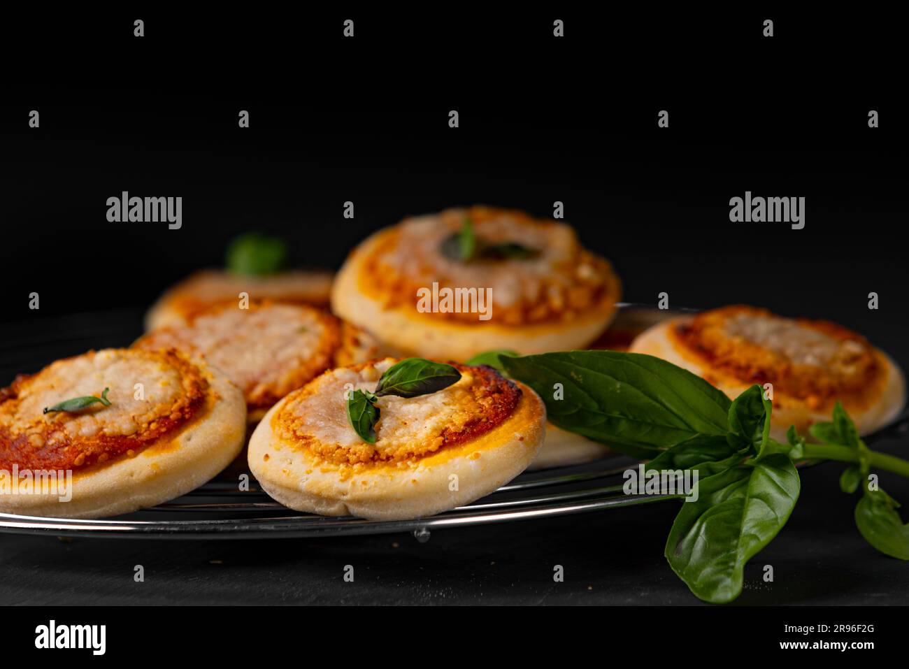 Mini Pizza Margherita, several on grid, basil, food photography, dark background Stock Photo