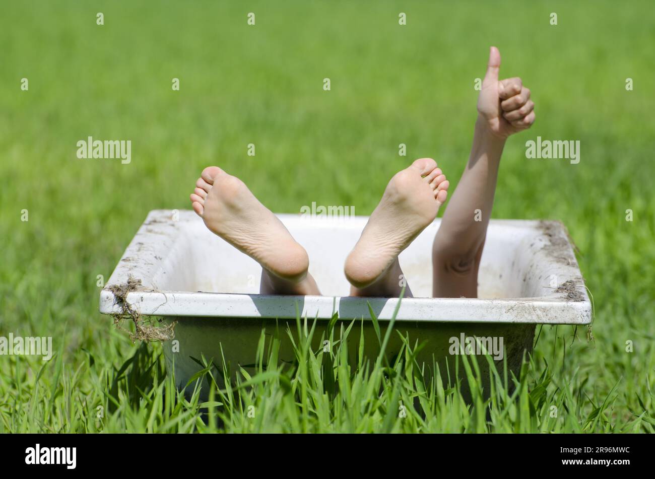 Woman Lying in a Bathtub on a Green Field and Showing OK Signal with