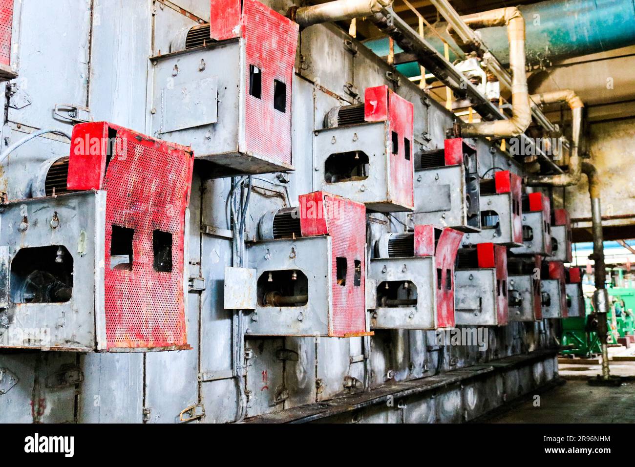 Iron metal red cabinets for perforated electric grid equipment located on a wall at an industrial petrochemical chemical refinery. Stock Photo