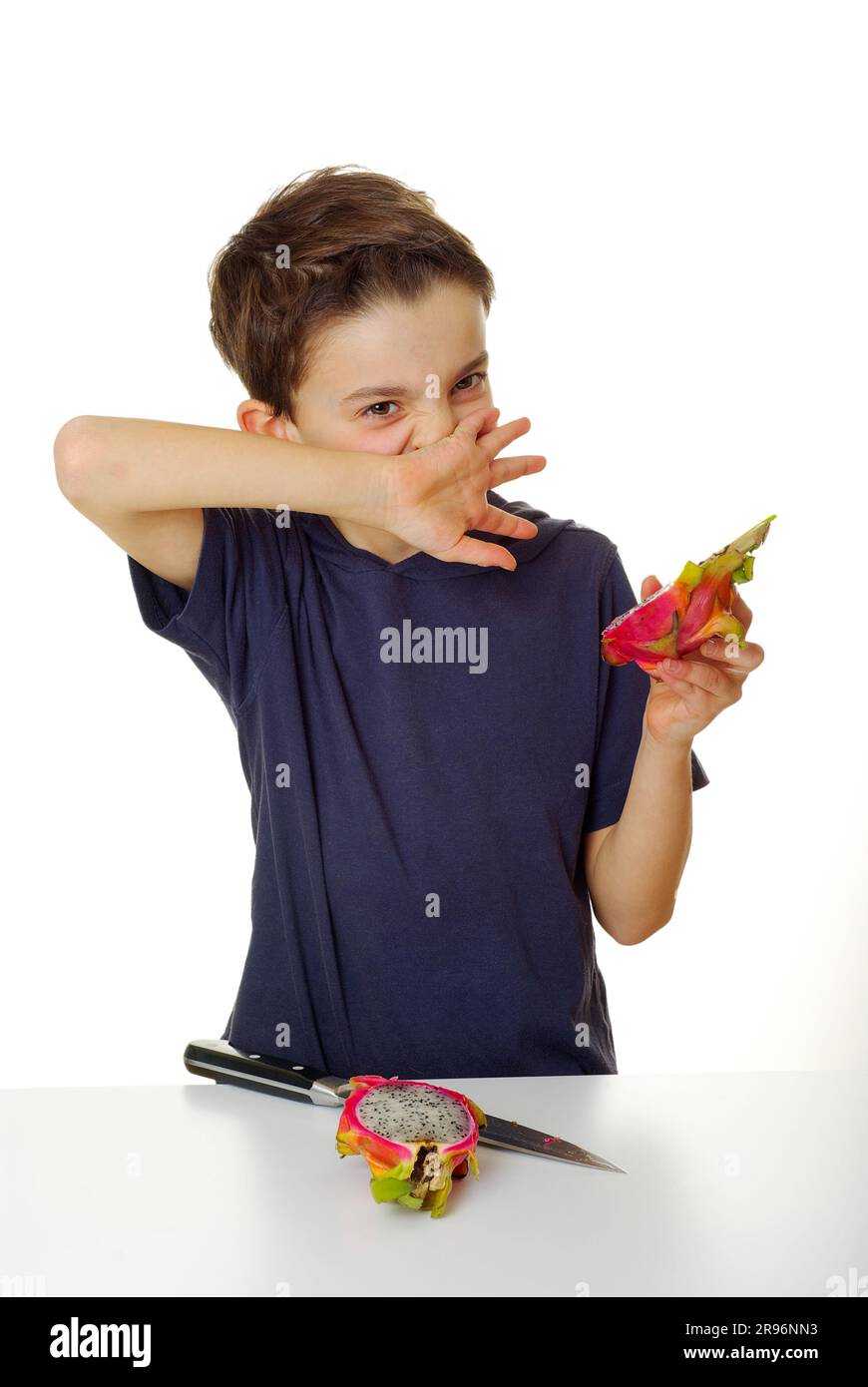 Boy with pitahaya and knife, wiping mouth with back of hand (Hylocereus triangularis), cactus fruit, dragon fruit, pitaya, wipe off Stock Photo