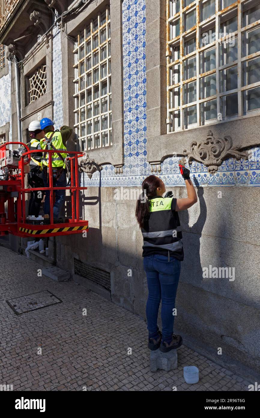 Woman restoring facade with azulejos, painted wall tiles, Igreja do Carmoa church, Porto, Portugal Stock Photo