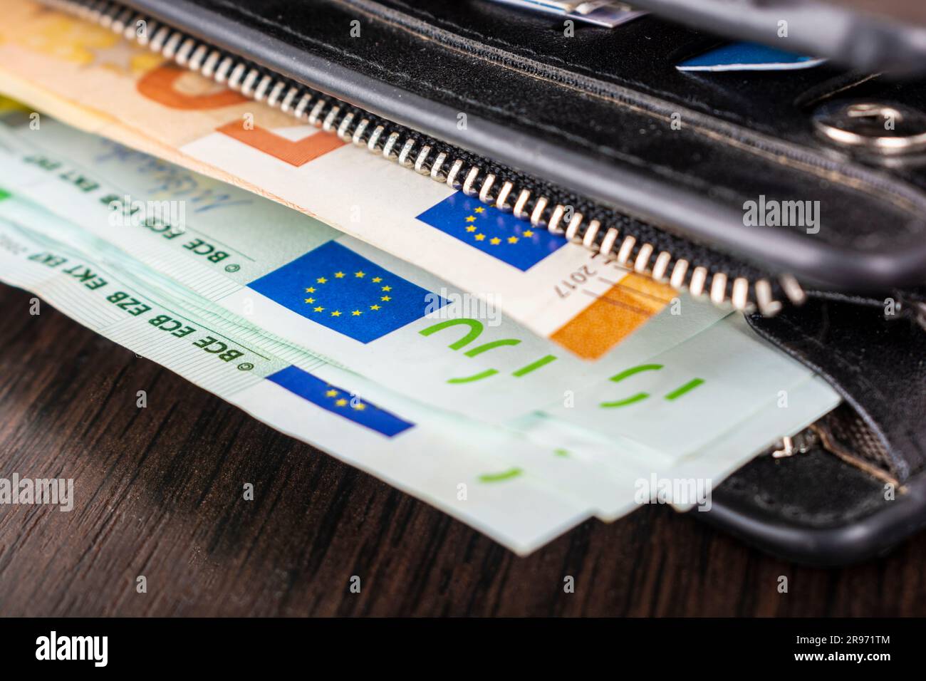 Open purse with euro cash denominations of denomination 10 20 50 100 on a wooden background. Men's wallet with cash euro. Stock Photo