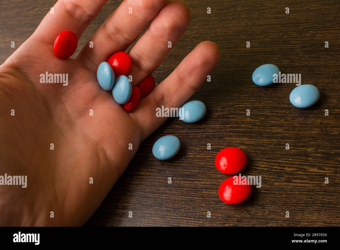 red and blue tablets in hand on the background of a wooden table Stock Photo