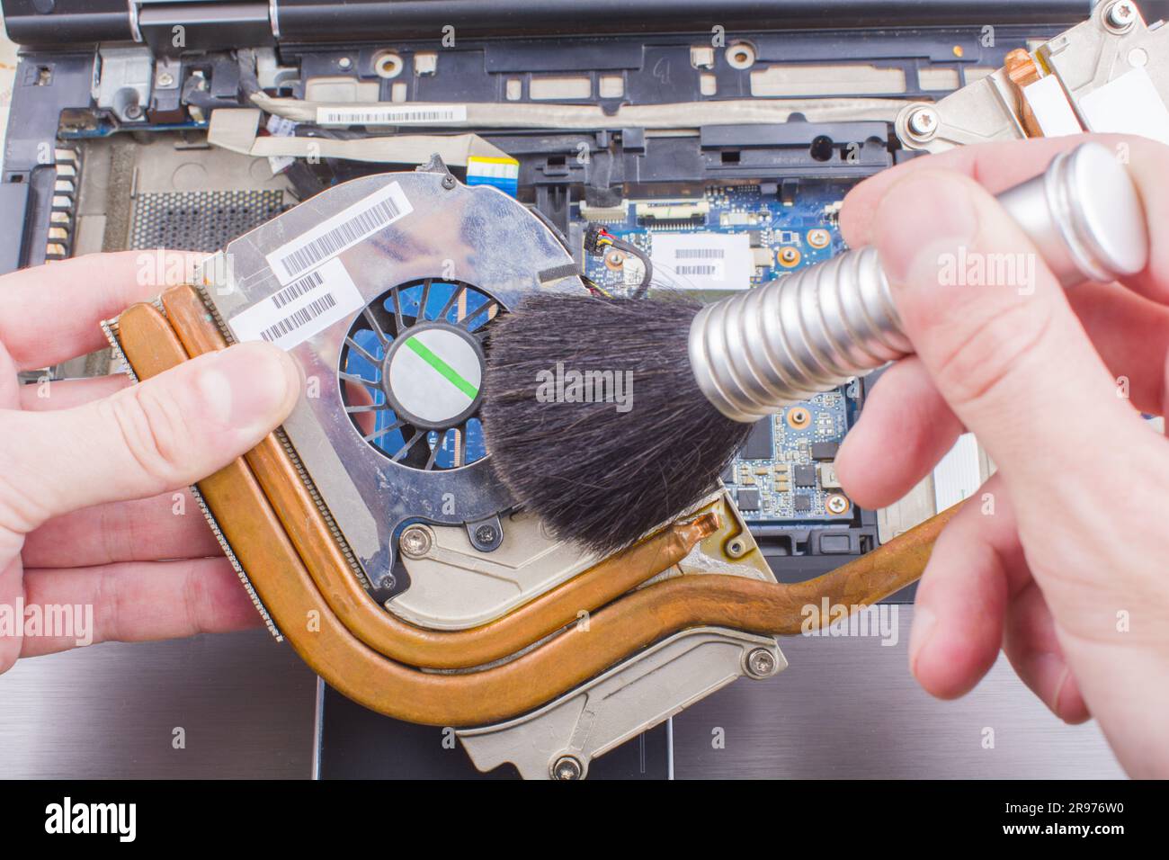 Man cleans the cooling system of the laptop cooler with a brush from the dust, close-up Stock Photo