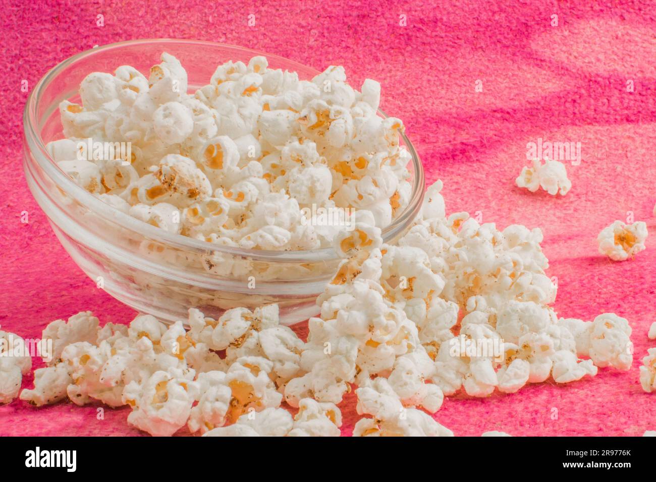 popcorn in a glass plate, on a pink uneven background Stock Photo