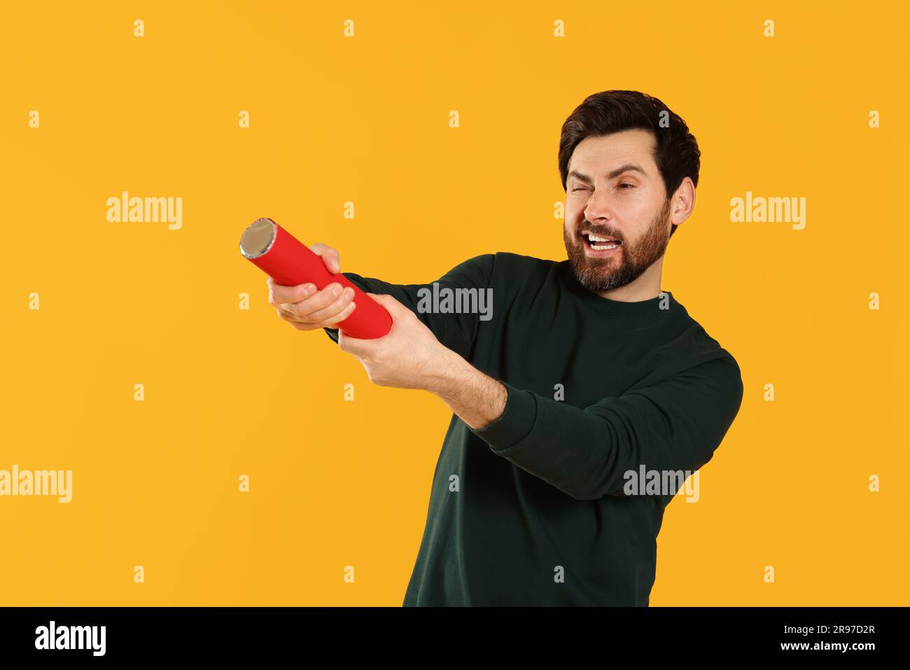 Handsome man with party popper on yellow background Stock Photo