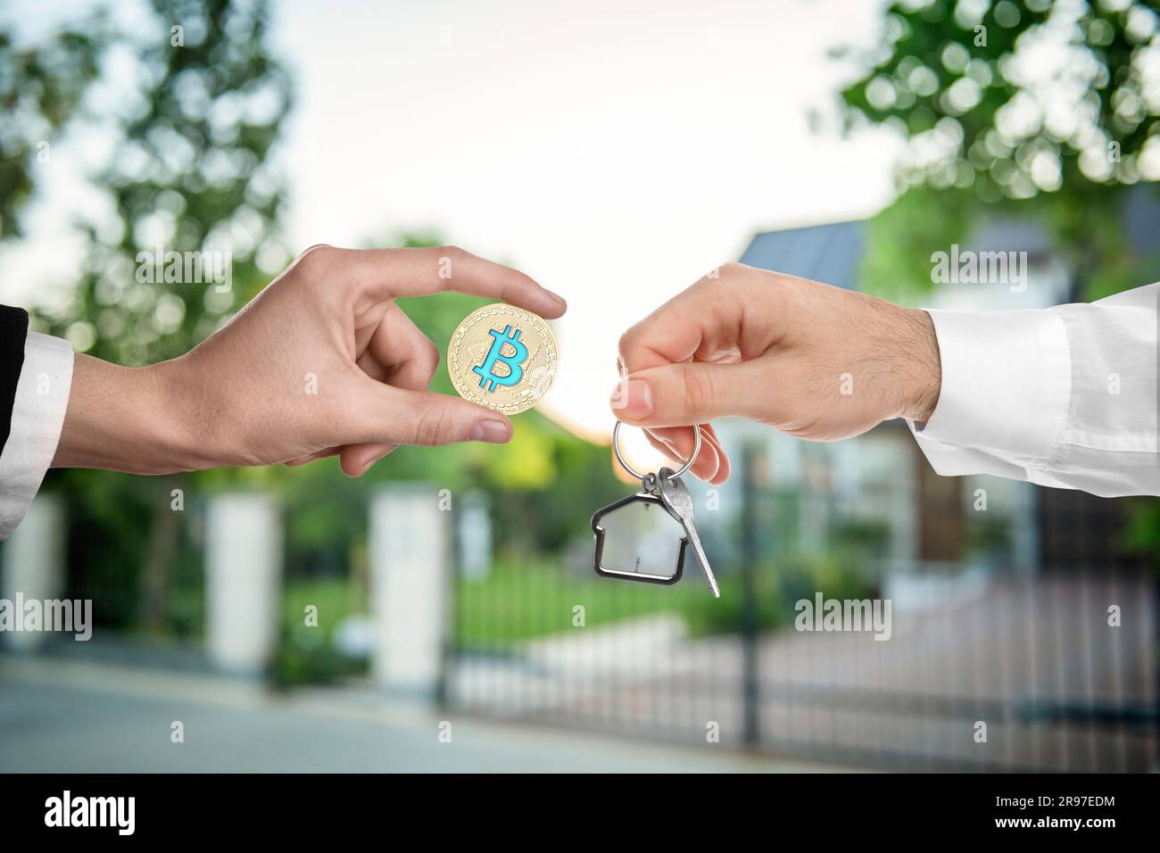 Bitcoin exchange. Man using cryptocurrency to buy house. Seller holding key  and buyer with bitcoin outdoors, closeup Stock Photo - Alamy