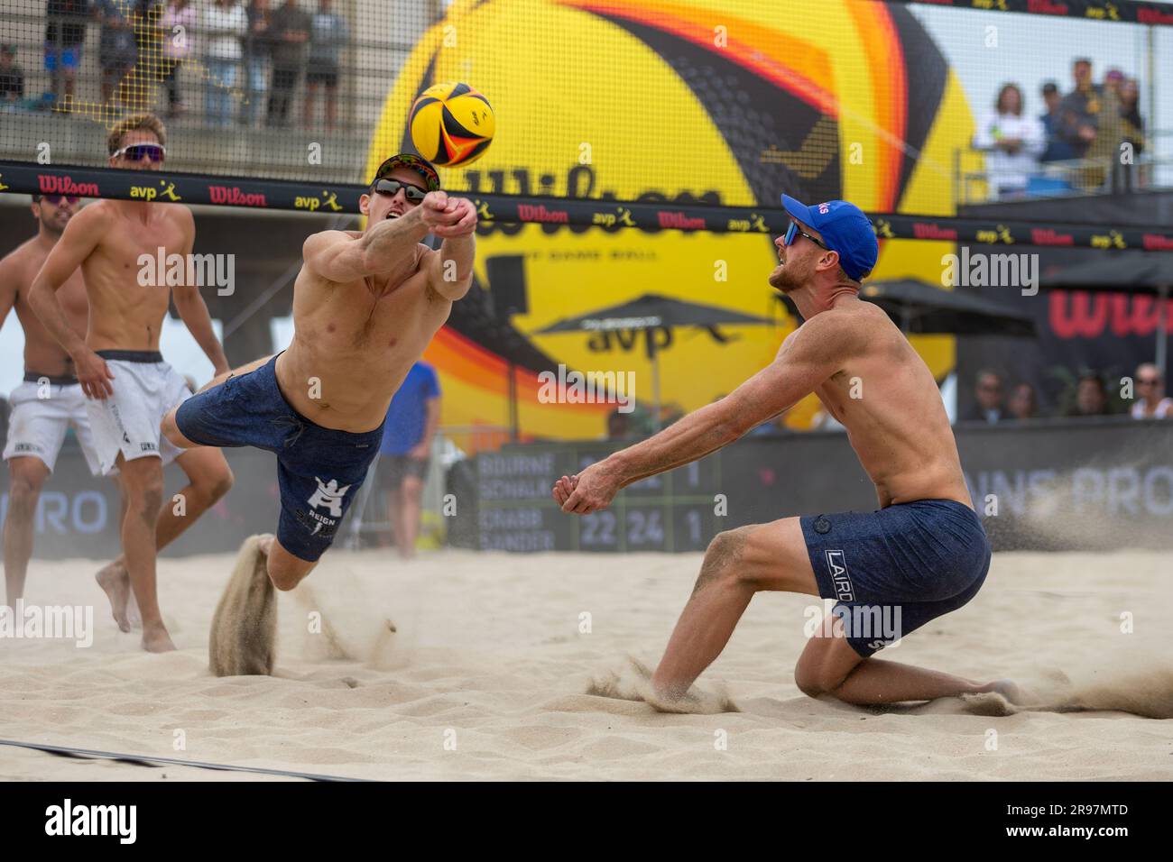 Tri Bourne lunges to dig the ball as Chaim Schalk looks on during the semifinal match of the AVP Huntington Beach Open (John Geldermann/Alamy) Stock Photo