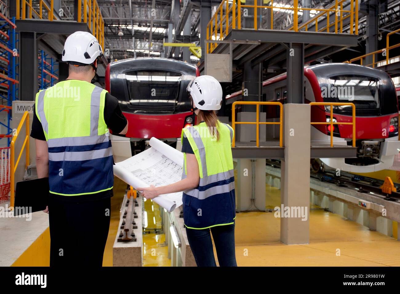Young caucasian engineer man and woman or worker looking blueprint and ...