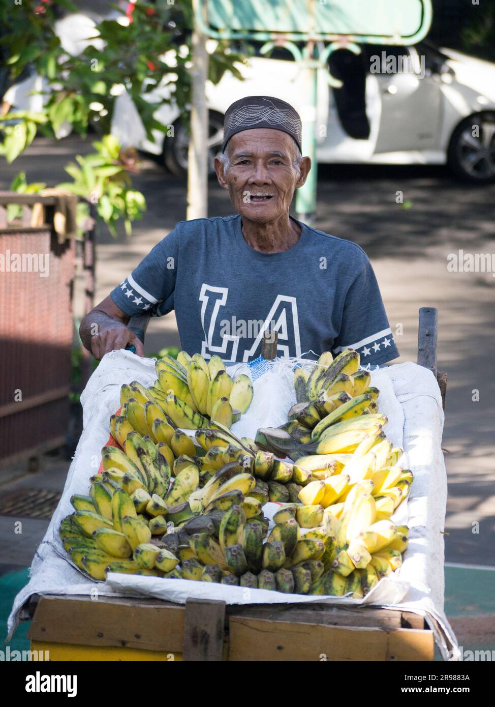 Jakarta, Indonesia - June 20, 2023 : portriat asian senior man traveling banana seller by cart smiling looking at the camera Stock Photo