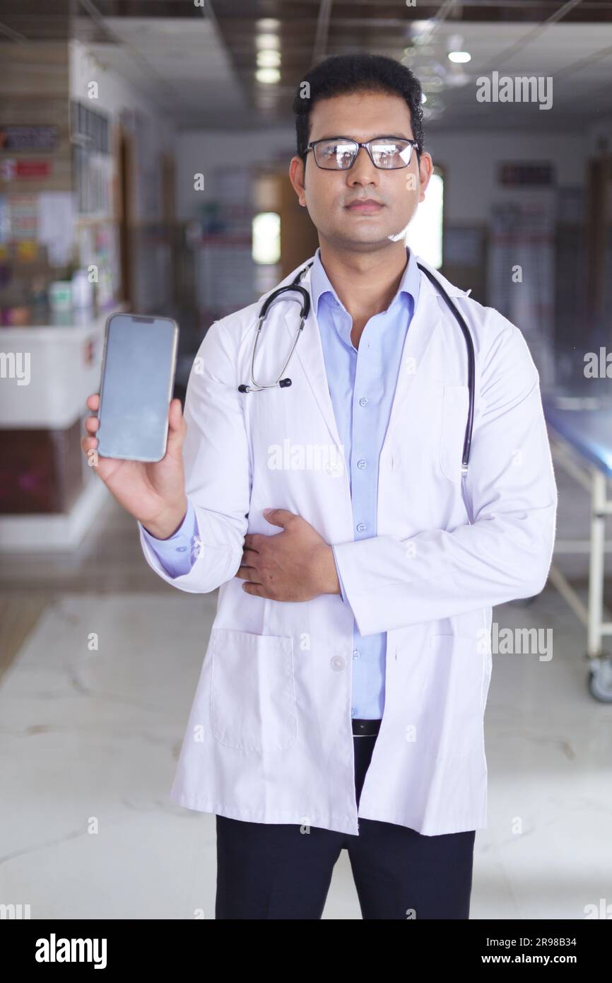 Portrait of smart young male doctor in white lab coat showing screen of