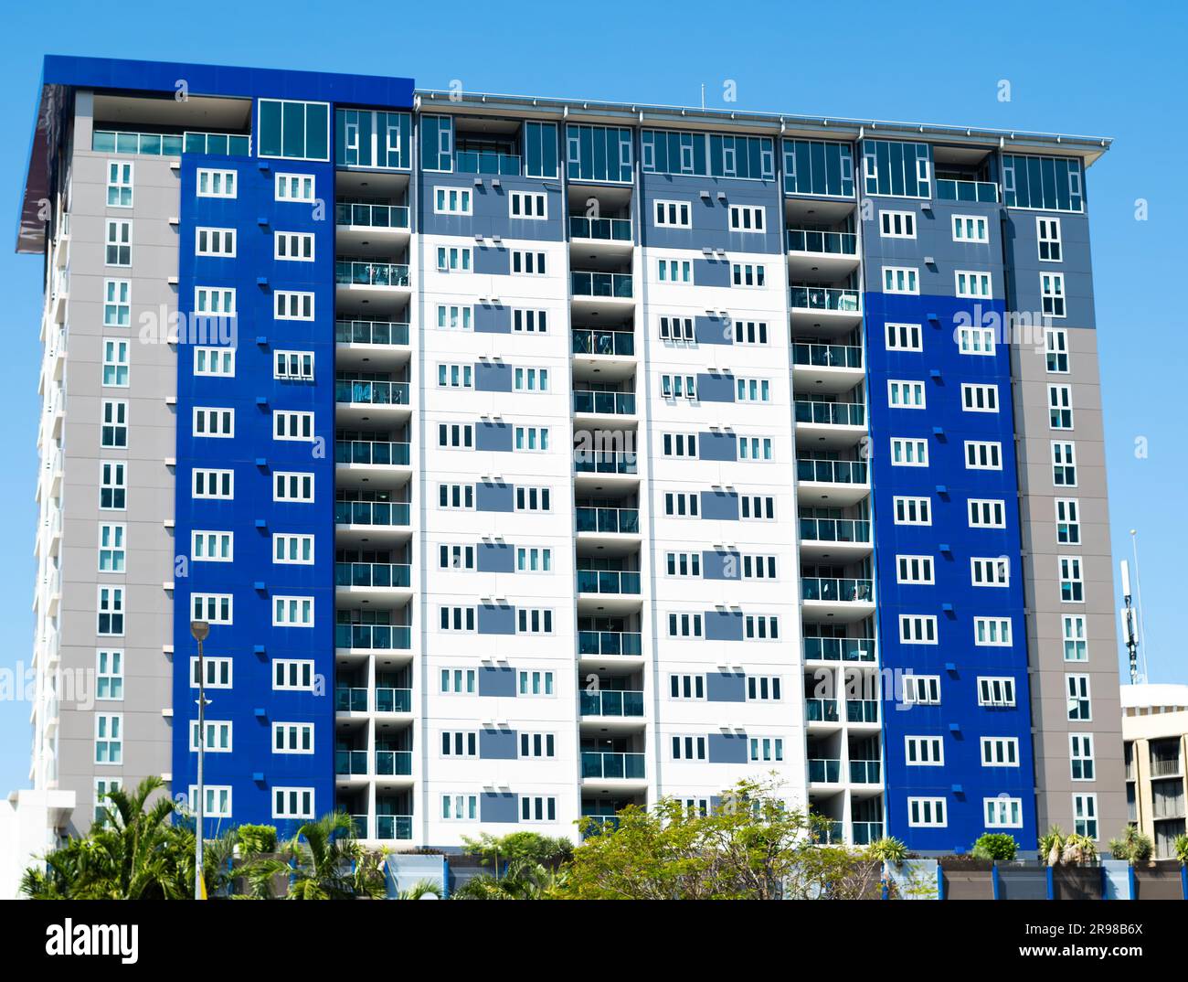 A blue, white and grey colored apartment block located in Darwin city, Australia, comprising a very simple design aesthetic. Stock Photo
