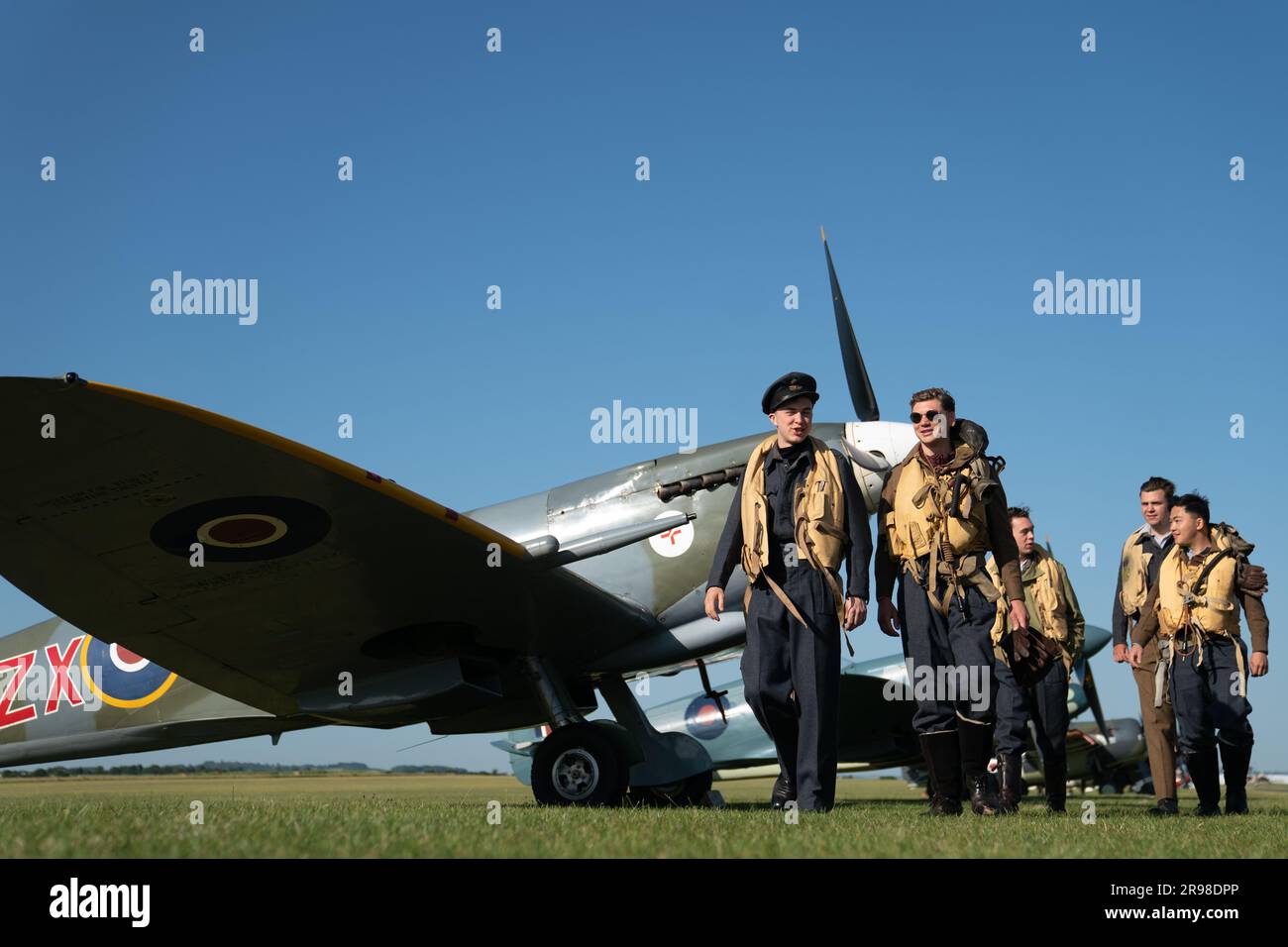 Spirit of Britain living history group walk past a Supermarine Spitfire during the annual Duxford Summer Air Show at IWM Duxford in Cambridgeshire. This year marks the 50th anniversary of the first air show at Duxford. Picture date: Sunday June 25, 2023. Stock Photo