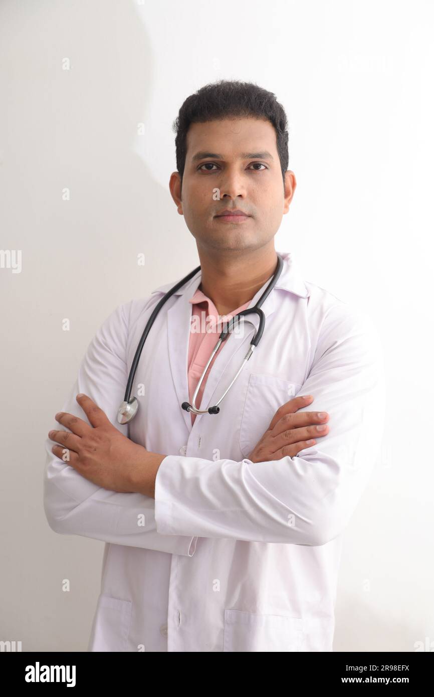 Senior female doctor in lab coat with arms crossed against white