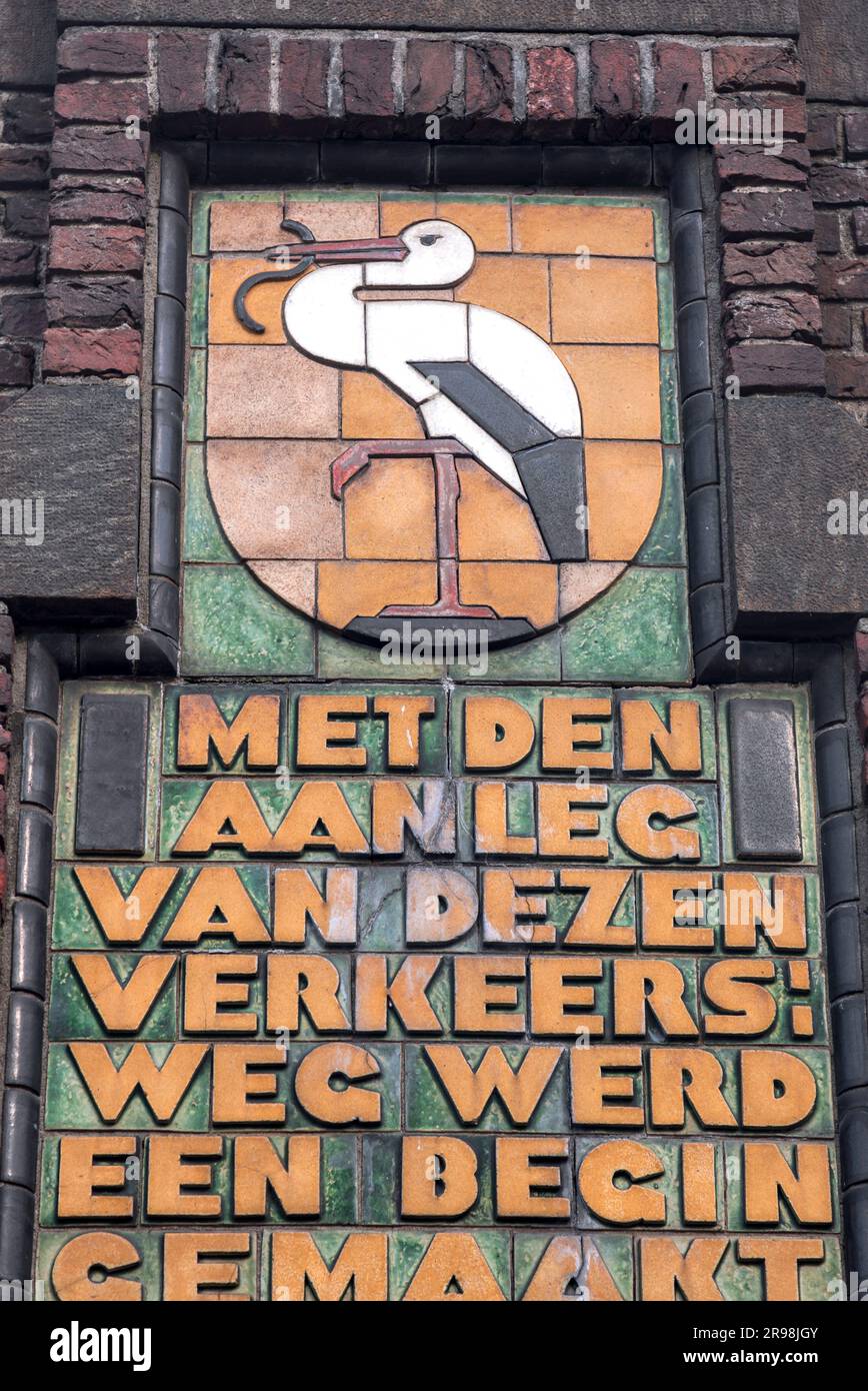 The Hague, NL - October 7, 2021: Old ceramic tile wall with a stork symbolizing The Hague city. Dutch text says: A start has been made with the constr Stock Photo