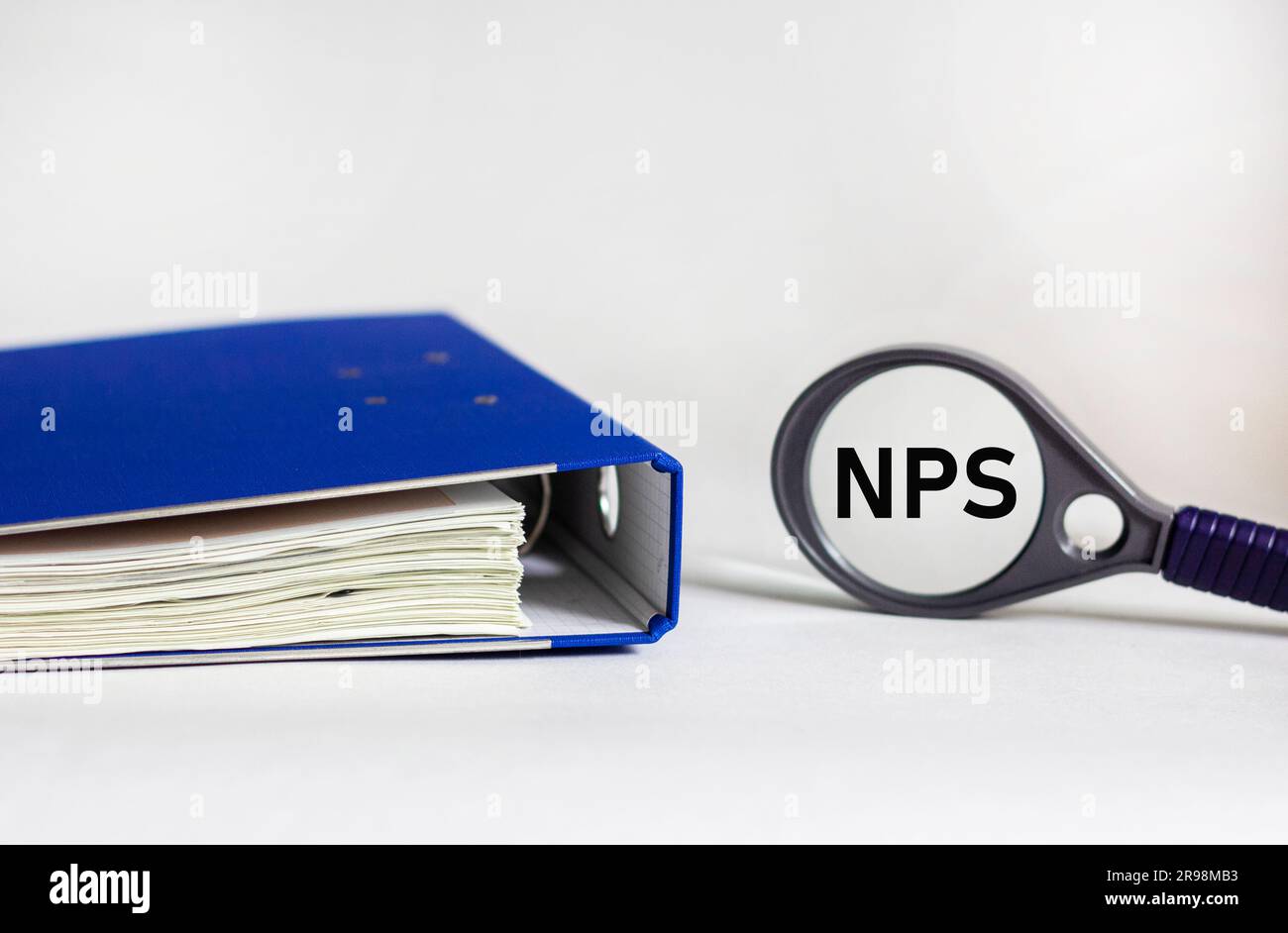 NPS concept on magnifying glass on white background with blue folder Stock Photo