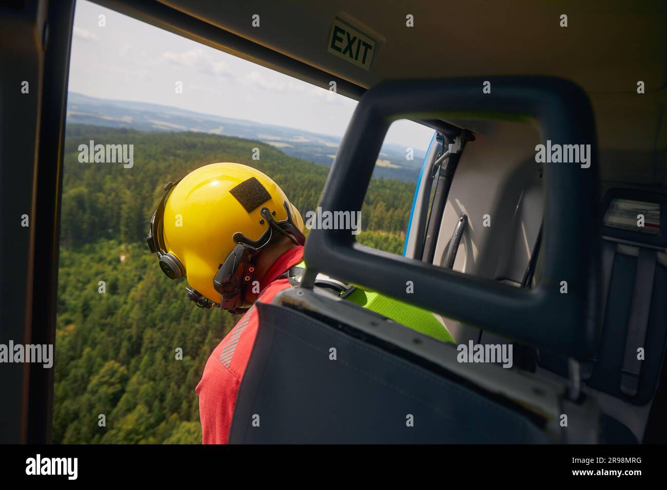 Rescue in difficult to access terrain. Paramedic of Helicopter Emergency Medical Service looking down from open door of  helicopter. Stock Photo
