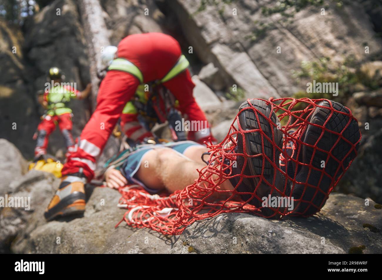 Rescue in difficult to access terrain. Doctor with paramedics of Emergency Medical Service treating injured patient and preparing him for transport by Stock Photo