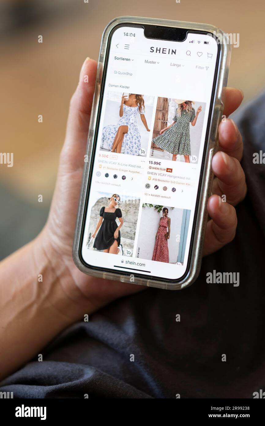 A woman visits the website of the Chinese fashion giant SHEIN on her mobile phone. Stock Photo