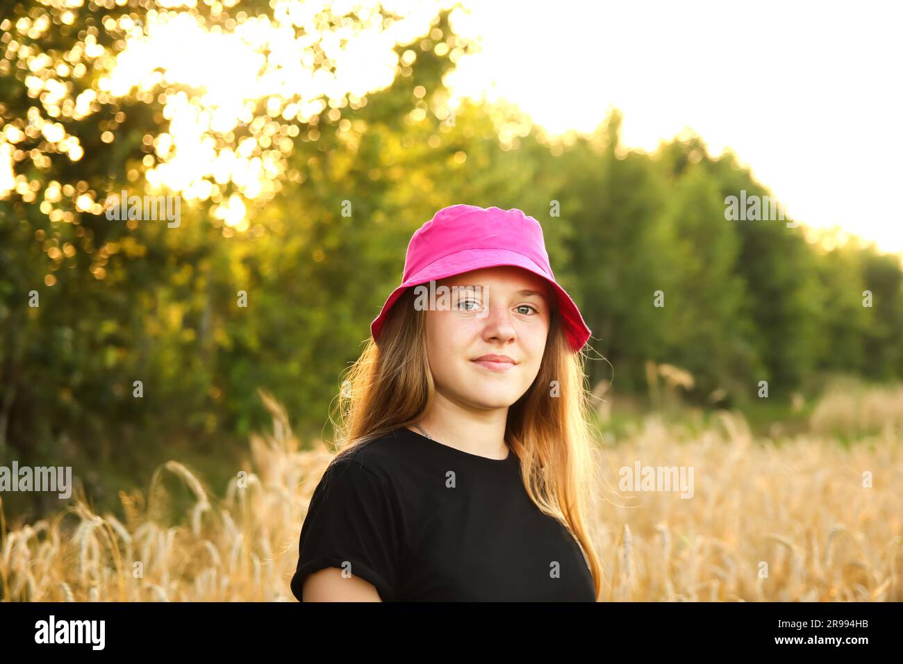 A cheerful teenage girl, aged 12 or 13, stands gracefully in a vibrant yellow summer background. Her radiant smile complements as she enjoying Stock Photo