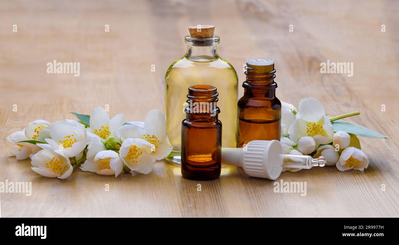 White jasmine flowers with green leaves and glass bottles with Essential oil Stock Photo