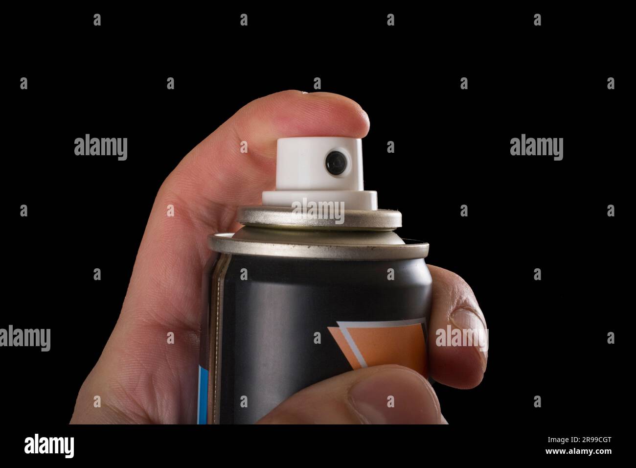 Close-up view of a human hand and pressed bottle of spray isolated on a black background Stock Photo