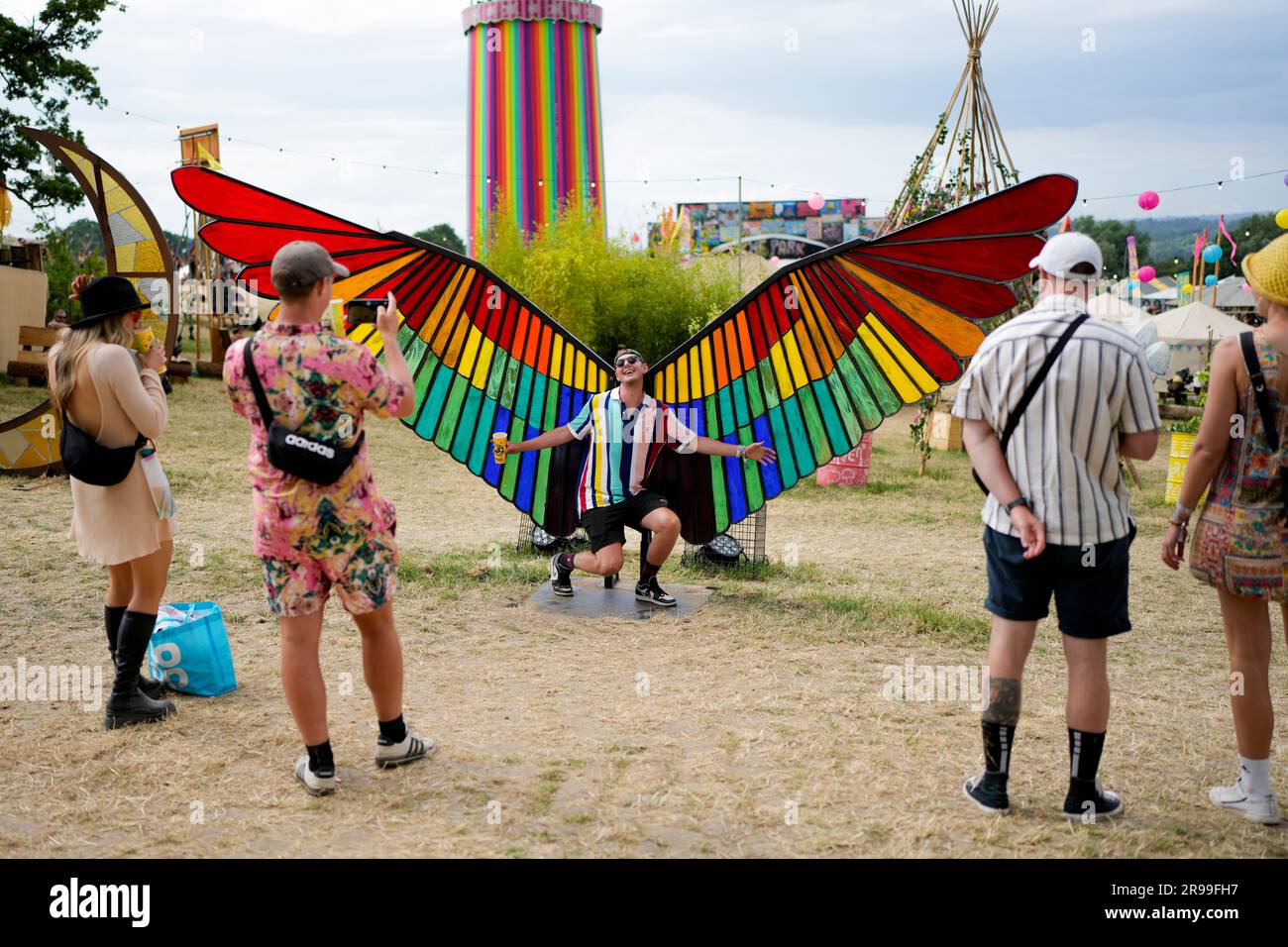 A festival goer poses for a photograph with a giant colourful wing