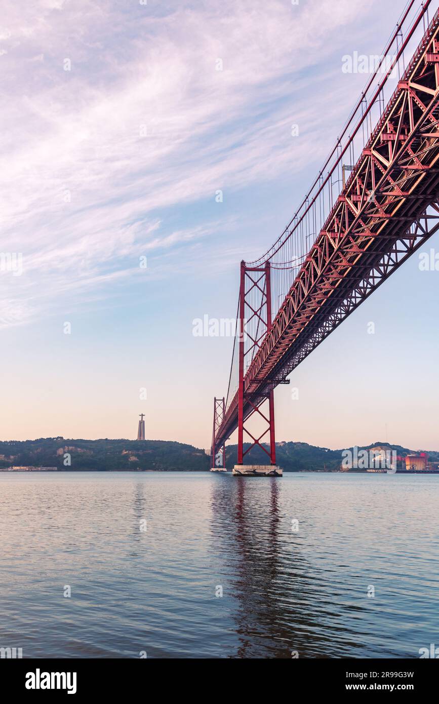 25 de Abril Bridge at sunrise with the Cristo Rey de Almada monument in ...
