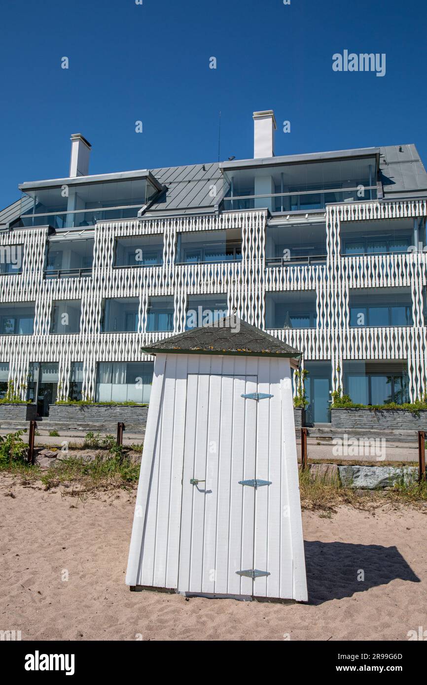 White beach changing cabin in front of a newly built residential building on a sunny summer day