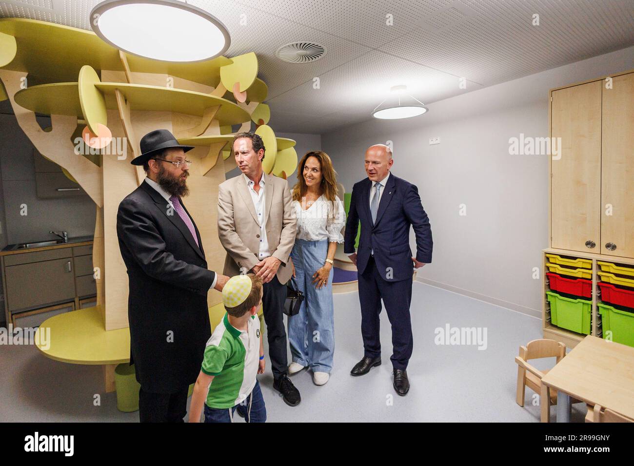 25 June 2023, Berlin: Rabbi Yehuda Teichtal (l-r), Trevor Pears (M), member of the board of the Pears Foundation, Daniela Pears and Kai Wegner, governing mayor of Berlin, stand in a room during a tour after the opening ceremony of the Pears Jewish Campus (PJC) in the building. The largest Jewish institution for education, culture and sports since the Shoah has opened in Berlin with a street party. The Pears Jewish Campus in Wilmersdorf offers 8,000 square meters of daycare, elementary and high school, art studios and music studios, a 100-seat cinema, and a sports and events hall. Photo: Carste Stock Photo
