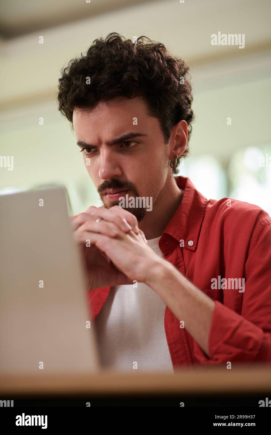 Frowning man looking at laptop screen with programming code Stock Photo