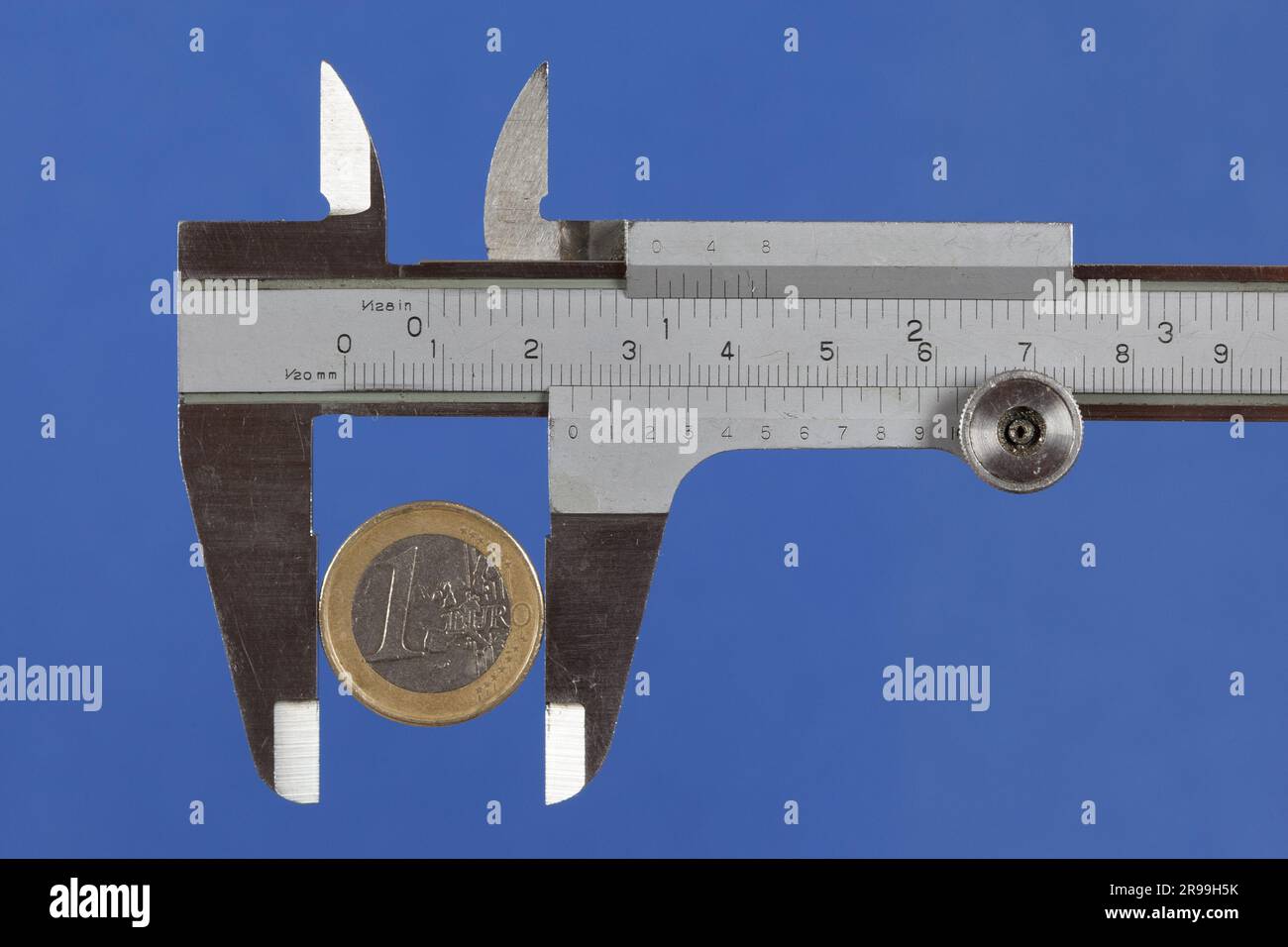 Euro coin in a caliper. How can you measure the value of money Stock