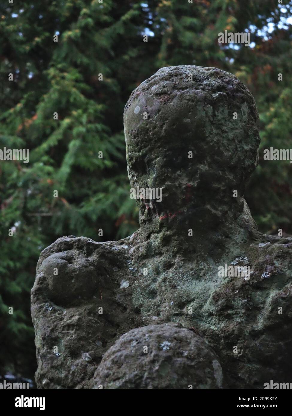 Closeup photo of destroyed statue showing all its imperfections. The contrast between beauty of the nature in the background and the damaged stone. Stock Photo