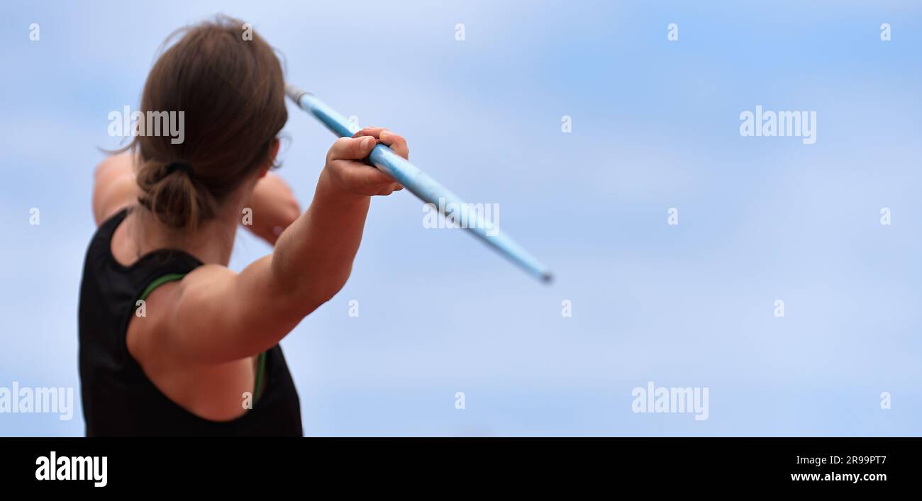 Female athlete throwing a javelin onto a grass field during a track and