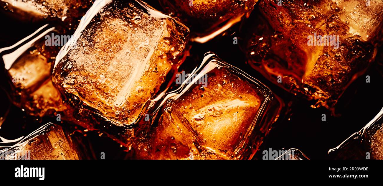 Cola with Ice. Close up of the ice cubes in cola water. Texture of carbonate drink with bubbles in glass. Cola soda and ice splashing fizzing or float Stock Photo