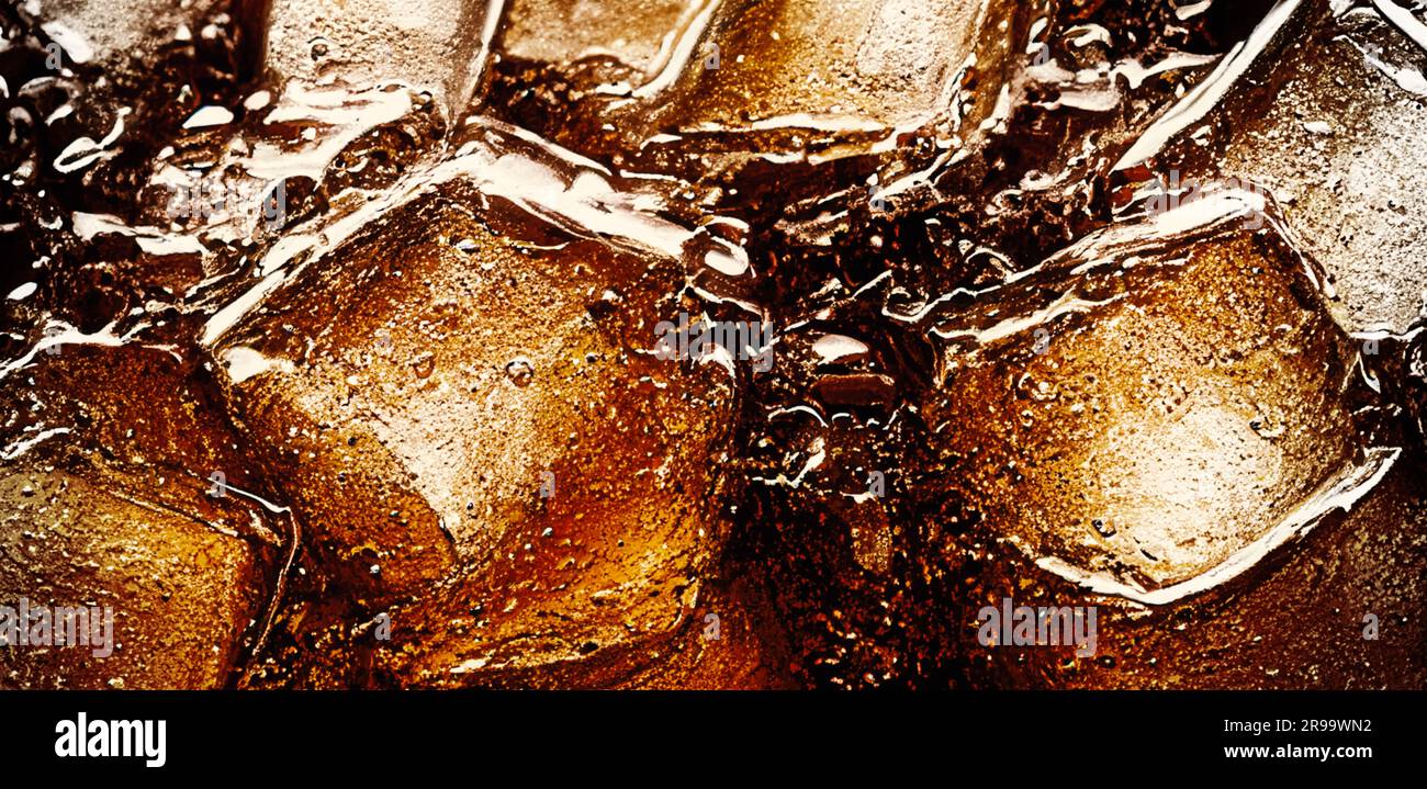 Cola with Ice. Close up of the ice cubes in cola water. Texture of carbonate drink with bubbles in glass. Cola soda and ice splashing fizzing or float Stock Photo