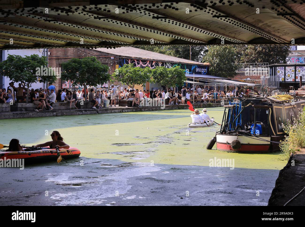 London, UK June 25th 2023. The hot weather caused the unusual sight of green algae covering the River Lea Navigation at trendy Hackney Wick in east London. The area was very busy as people enjoyed the hot sunshine.  Credit: Monica Wells/Alamy Live News Stock Photo