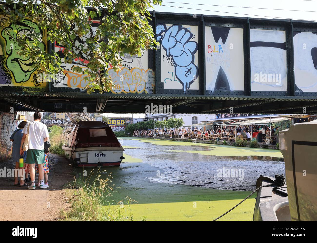 London, UK June 25th 2023. The hot weather caused the unusual sight of green algae covering the River Lea Navigation at trendy Hackney Wick in east London. The area was very busy as people enjoyed the hot sunshine.  Credit: Monica Wells/Alamy Live News Stock Photo