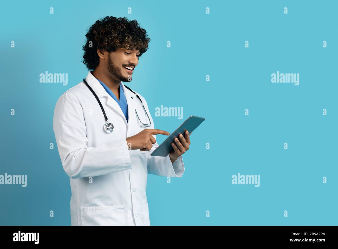 Positive young eastern doctor using digital tablet, copy space Stock Photo