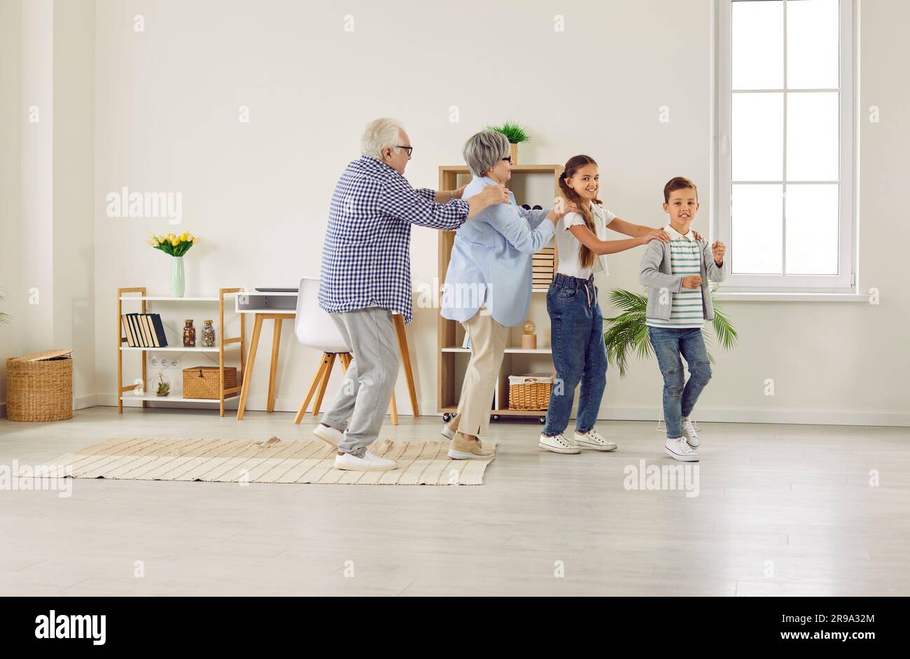 Happy, funny grandparents and children playing games, dancing and having fun together Stock Photo