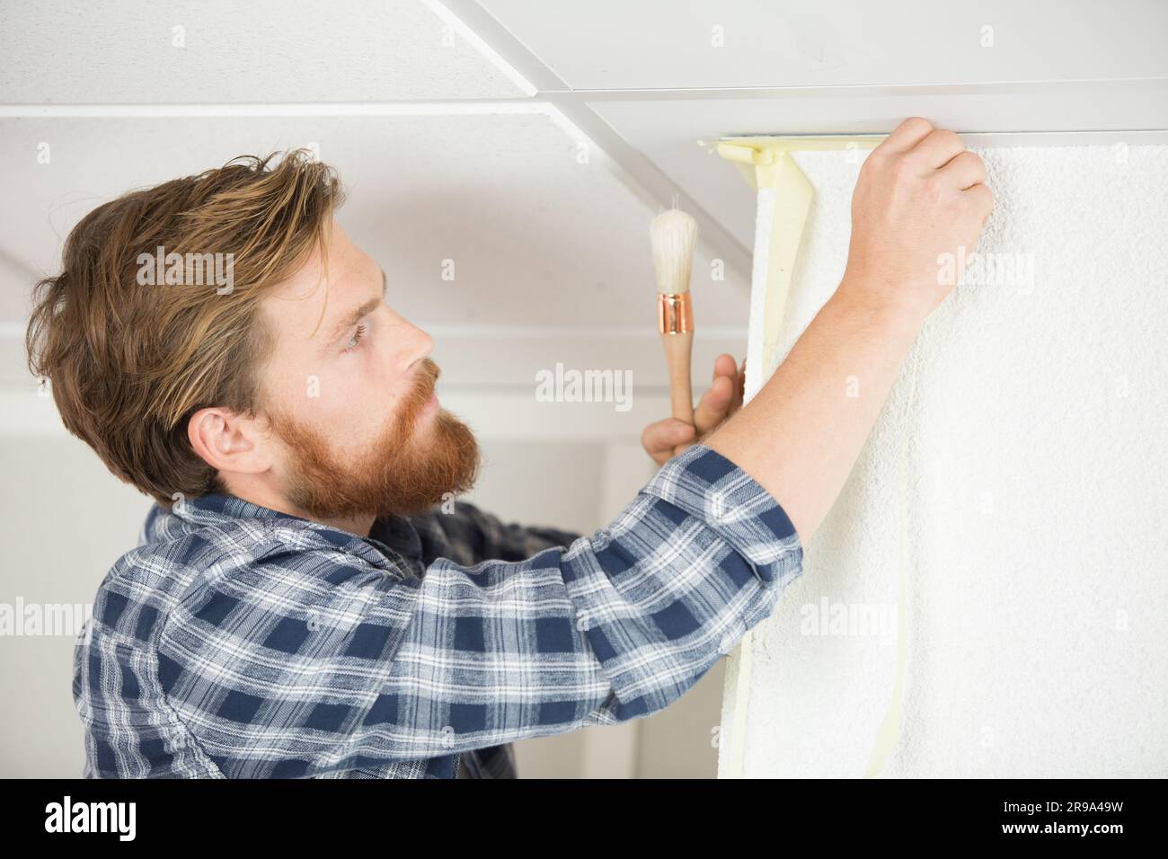 painter using brush to cut in around ceiling Stock Photo Alamy