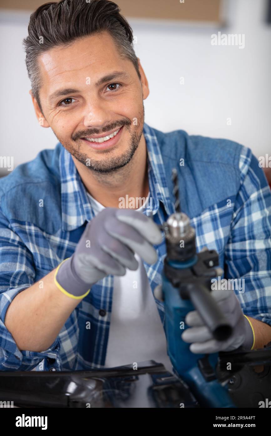 workman changing drill bit on his power tool Stock Photo