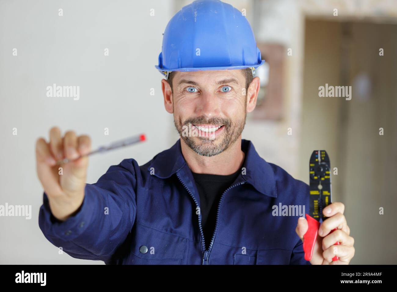 portrait of a happy young male builder showing tools Stock Photo