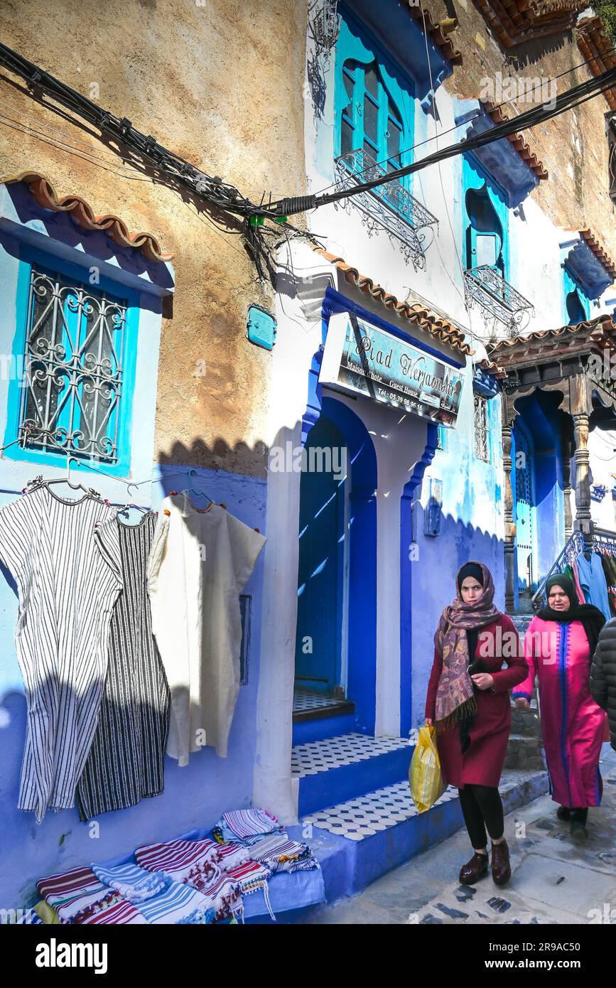 Locals, tourists and vendors crowd the small streets built centuries ago now known for their blue walls and stairs and doors in Chefchaouen, Morocco Stock Photo
